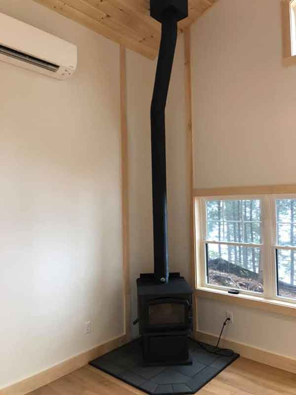 small black wood stove in corner of room. next to windows and with hard wood floors