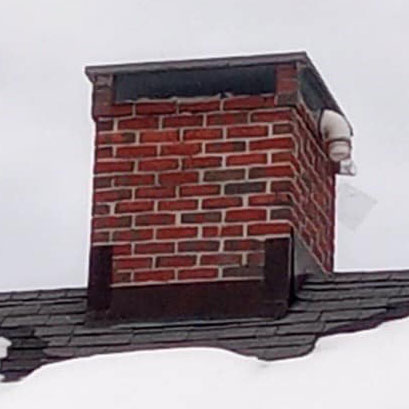 brick chimney with black flashing on roof of home with snow on bottom of roof