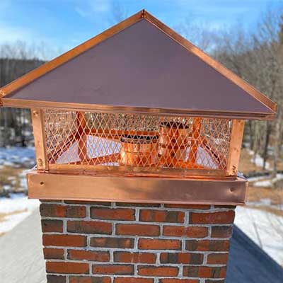 New metal copper colored chimney cap on chimney shown close up
