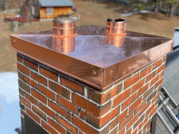 close up of brick chimney with copper colroed metal chase cover