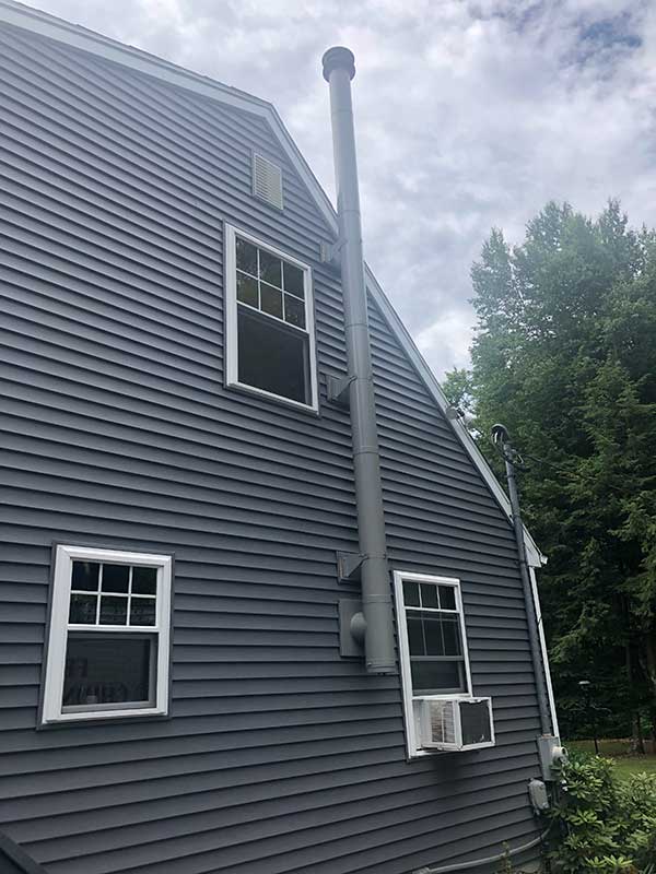 side of multi level home showing class a chimney pipe mounted and running up the side of home